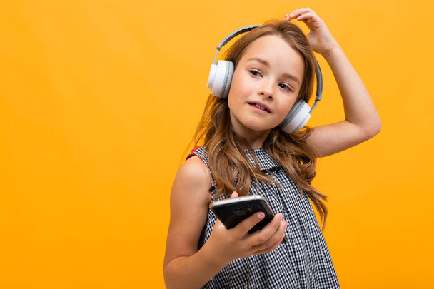 linda niña escuchando música posando sobre fondo naranja
 - Foto, Imagen