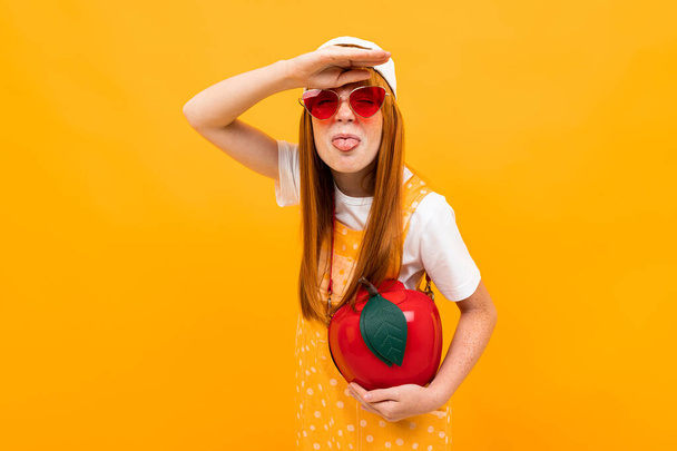 emotioneel gember meisje in zonnebril poseren tegen oranje achtergrond  - Foto, afbeelding