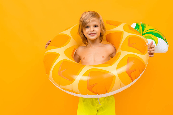 Niedlicher kleiner Junge mit Gummiring posiert vor orangefarbenem Hintergrund  - Foto, Bild