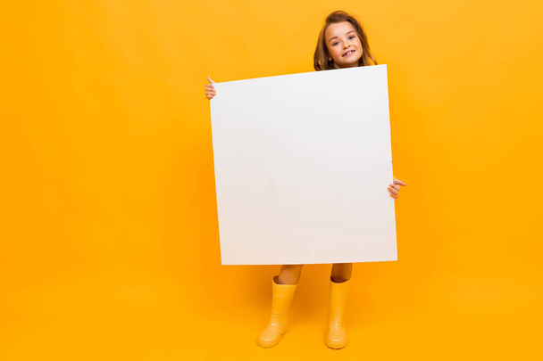 κοριτσάκι με λευκό πίνακα σε πορτοκαλί φόντο  - Φωτογραφία, εικόνα