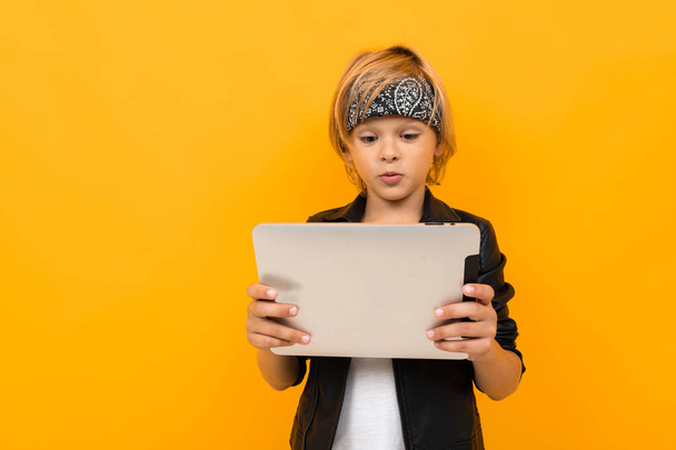 chico de moda sosteniendo la tableta contra fondo naranja
  - Foto, imagen