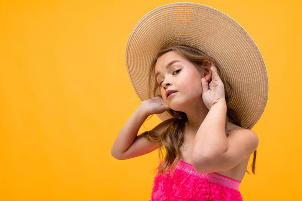 beautiful emotional little girl in straw hat posing against orange background  - Fotoğraf, Görsel