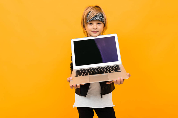 chłopiec z laptopem pozowanie przeciwko pomarańczowy  - Zdjęcie, obraz