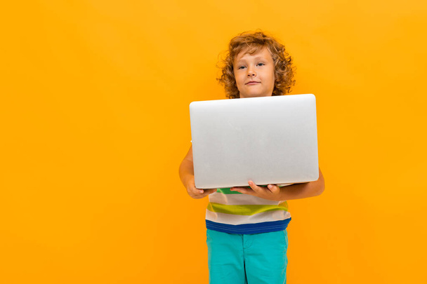 schöner Junge mit Laptop vor orangefarbenem Hintergrund  - Foto, Bild