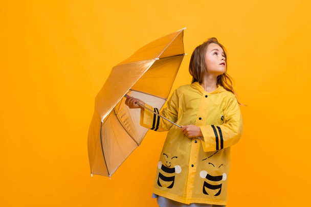 мила маленька дівчинка в плащі з парасолькою
  - Фото, зображення