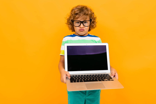 schöner Junge mit Laptop vor orangefarbenem Hintergrund  - Foto, Bild