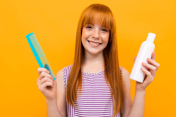 teenage girl with red hair posing with hairbrush against orange background  - Foto, Imagem