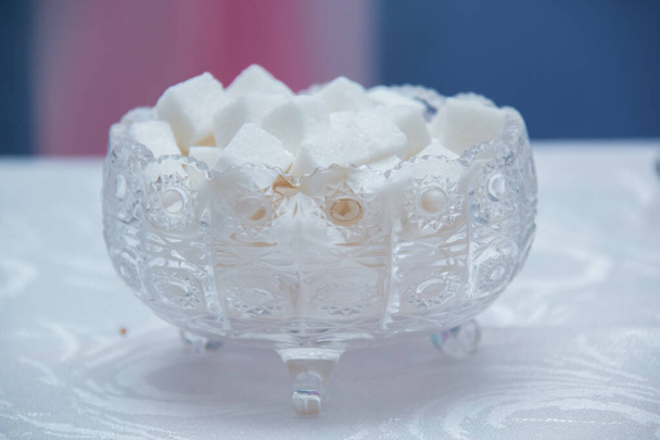 Γυάλινο μπολ γεμάτο κύβους ζάχαρης. κύβους ζάχαρης σε μπολ απομονώνονται σε λευκό φόντο . - Φωτογραφία, εικόνα