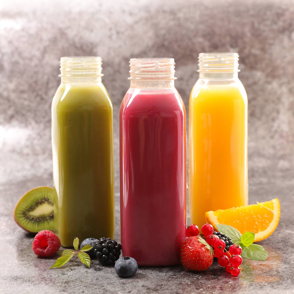 bottle of fruit juice with orange, kiwi and berry fruit - Foto, imagen