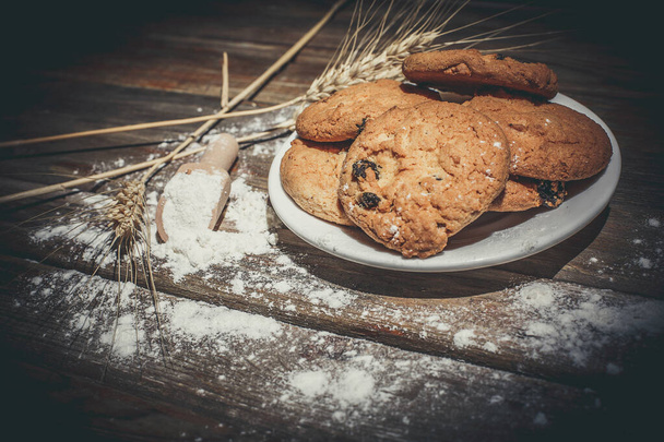 Oatmeal gingerbread cookies with raisins, flour and ears of wheat on a wooden surface - Foto, Imagem