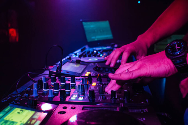 DJ hand mixes on a professional mixer in a nightclub - Photo, image