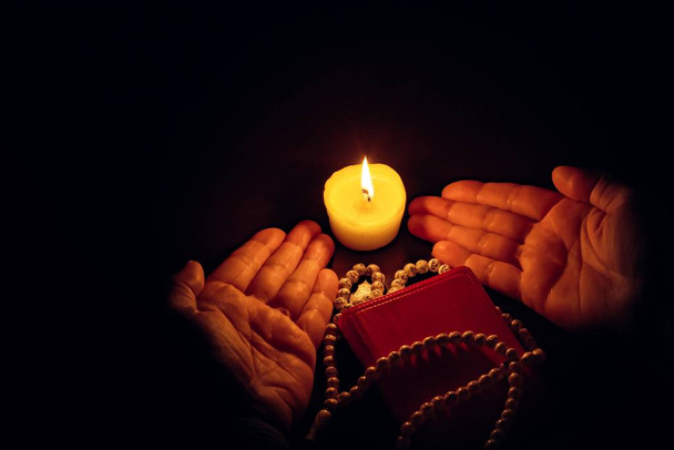 Praying hands, Islamic background . The holy Koran under candlelight . Book in candlelight - Photo, Image
