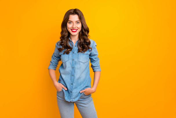 Photo of cheerful cute nice charming gorgeous girl smiling toothily holding hands in pockets isolated over yellow vivid color background - Zdjęcie, obraz