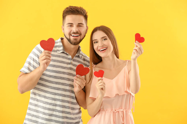 Portrait of happy young couple with paper hearts on color background - Фото, изображение