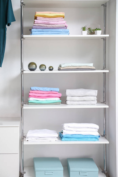 Stacked clean clothes on shelves in show room - Photo, Image