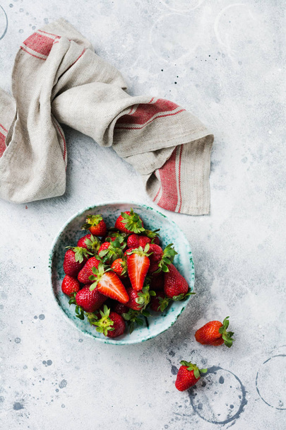 Fresh strawberry in old ceramic bowl rustic with green leaves on gray concrete background. Healthy breakfast concept. Top view. - Valokuva, kuva