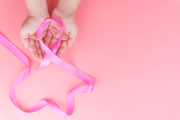 Женщина держит в руках розовую ленту рак груди на розовом фоне
 - Фото, изображение