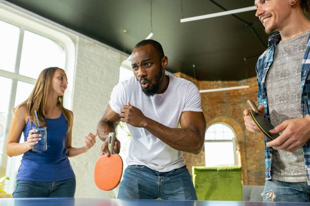 Young people playing table tennis in workplace, having fun - Foto, afbeelding