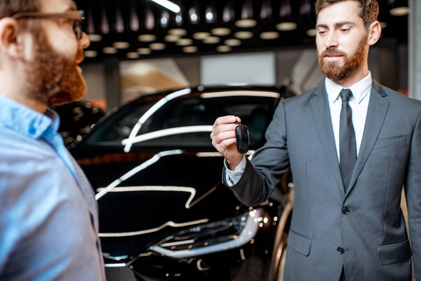 Cliente com um vendedor no showroom com carros elétricos
 - Foto, Imagem