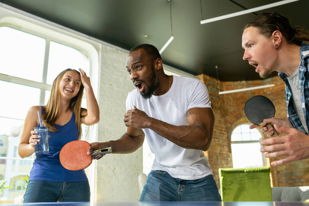 Gençler iş yerinde masa tenisi oynuyor, eğleniyorlar. - Fotoğraf, Görsel
