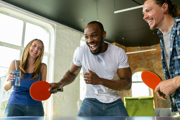Young people playing table tennis in workplace, having fun - Foto, afbeelding