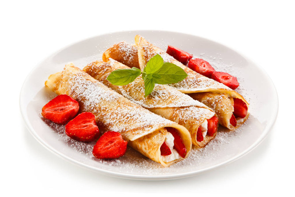 Crepes with strawberries and cream on white background  - Фото, зображення