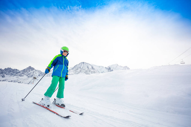 glücklicher Skifahrer, frühpubertärer Junge in Schutzbrille und Helm, beim Skifahren auf der Piste schnell rutschend - Foto, Bild