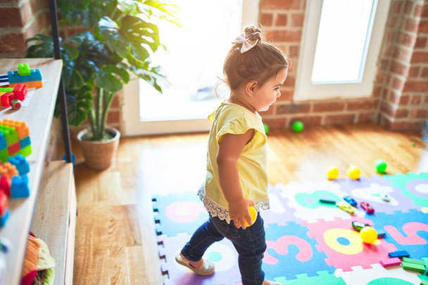 Hermoso niño de pie alrededor de un montón de juguetes en el jardín de infantes
 - Foto, imagen