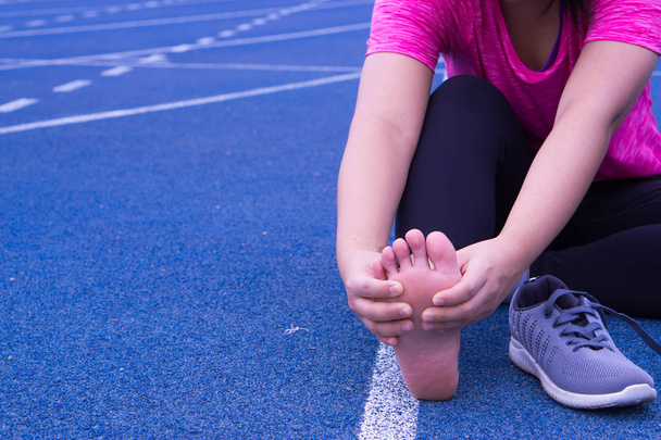 Young woman massaging her painful foot from jogging and running  - Photo, Image