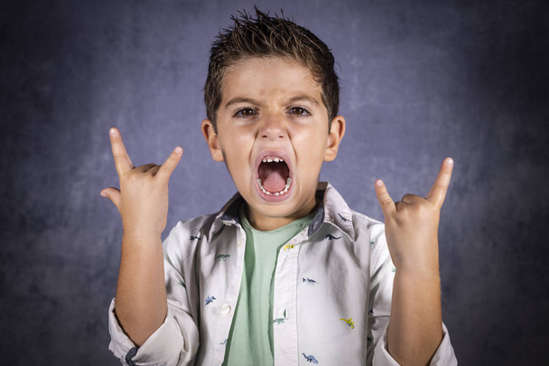 Šťastné roztomilé dítě křičí a dělá heavy metal rock sig - Fotografie, Obrázek