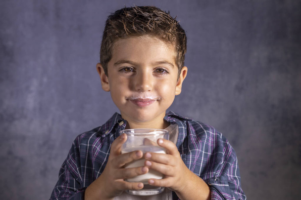 Little child enjoying with a glass of milk - Fotó, kép