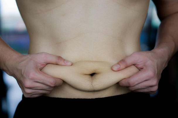 Acercarse hombre sosteniendo el vientre gordo excesivo. Hombre con sobrepeso abdomen
 - Foto, imagen