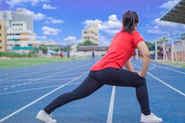 Młoda kobieta rozprostowuje nogi przed bieganiem i ćwiczeniami. Y - Zdjęcie, obraz