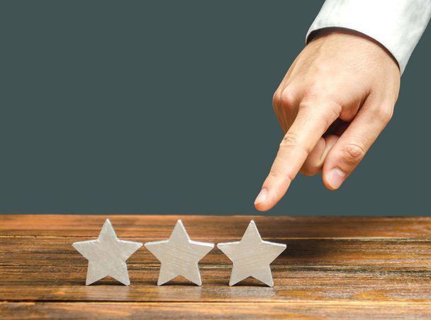 Critic points to third star. The concept of the rating of hotels and restaurants. The evaluation of visitors. Quality level, good service. Customer rating. Feedback. - Φωτογραφία, εικόνα