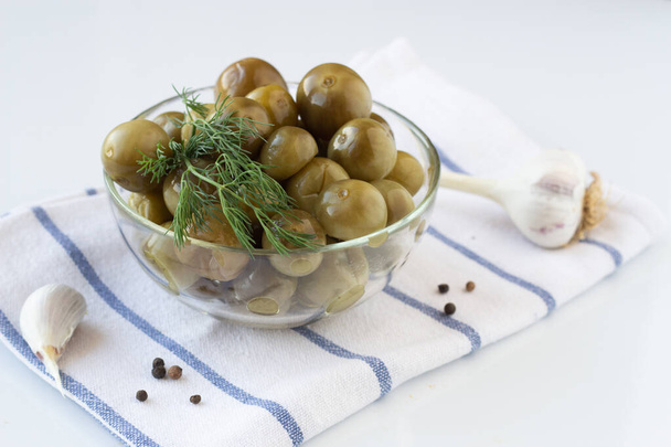 Sour green cherry tomatoes with dill in a glass plate on a white towel on a white background - Photo, Image