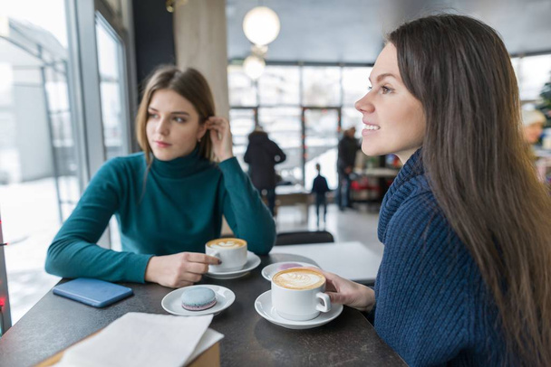 二人の若いです美しい女性カフェでコーヒーを飲みながら休憩中に話して - 写真・画像