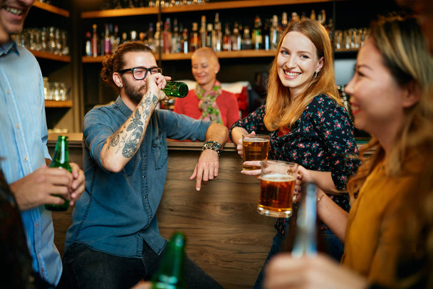 Eine Gruppe von Freunden trinkt Bier, plaudert und amüsiert sich in der Kneipe. Ausgehen. - Foto, Bild