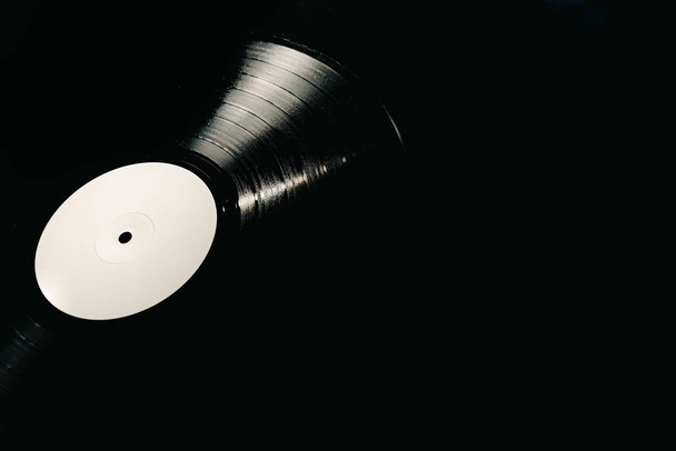 Vinylplaat op zwarte achtergrond verlicht, kopieerruimte - Foto, afbeelding