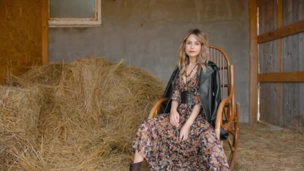 Giovane donna che oscilla su una sedia a dondolo in un ranch
. - Filmati, video