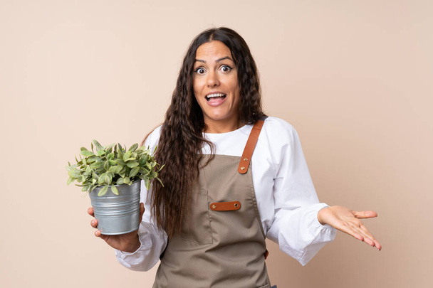 Jeune femme tenant une plante avec une expression faciale choquée
 - Photo, image