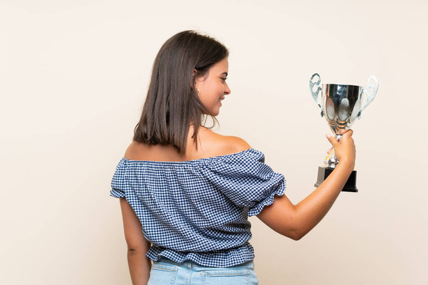 Young girl over isolated background holding a trophy - Valokuva, kuva