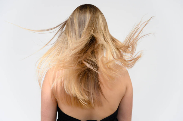 Studio large photo portrait of a beautiful girl with long beautiful fluttering hair on a white background. Back view. - Φωτογραφία, εικόνα