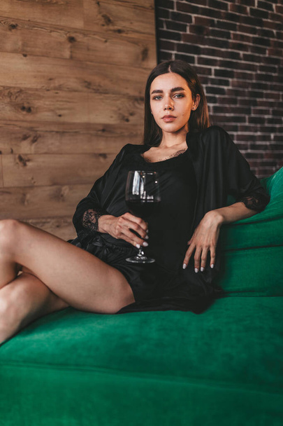 Egy gyönyörű hölgy reggel szexin pózol egy pohár borral a kezében, pizsamában. - Fotó, kép