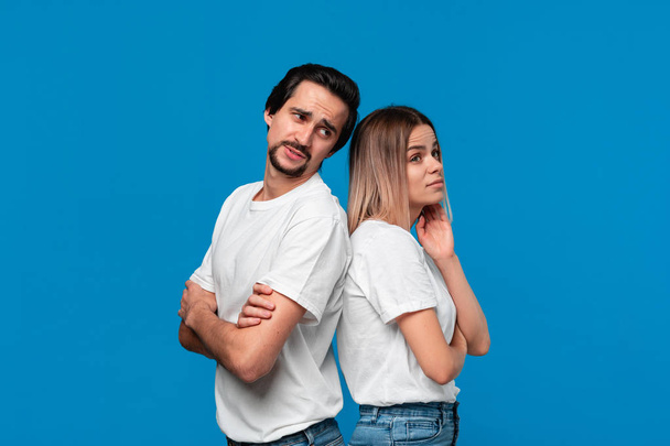 Couple of a young blond woman and brunet bearded man with mustaches in white t-shirts and blue jeans disputing about important issues. - Fotografie, Obrázek