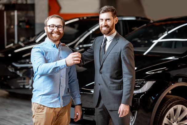 Client with a salesman at the showroom with electric cars - Zdjęcie, obraz