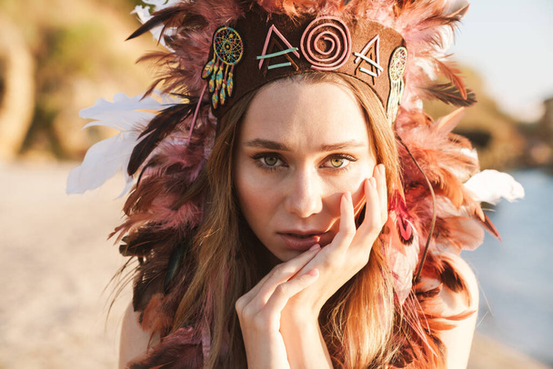 Image of hippy girl in indian chief feather headdress walking by - 写真・画像