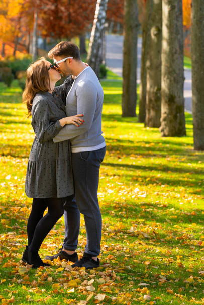 若いですカップルで愛キスで秋の公園 - 写真・画像
