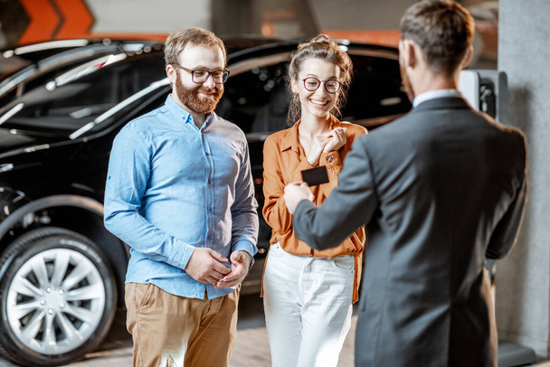 Couple with a seller at the car dealership - Foto, imagen