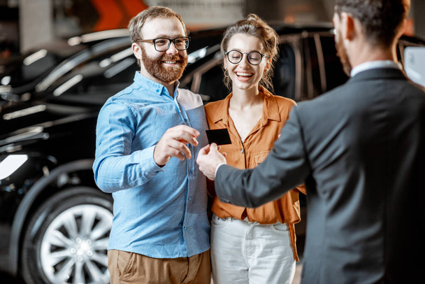Couple with a seller at the car dealership - Foto, afbeelding