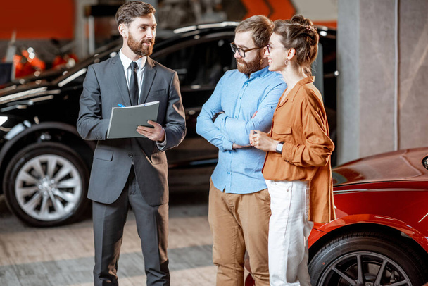 Couple with sales manager in the car dealership - Foto, afbeelding